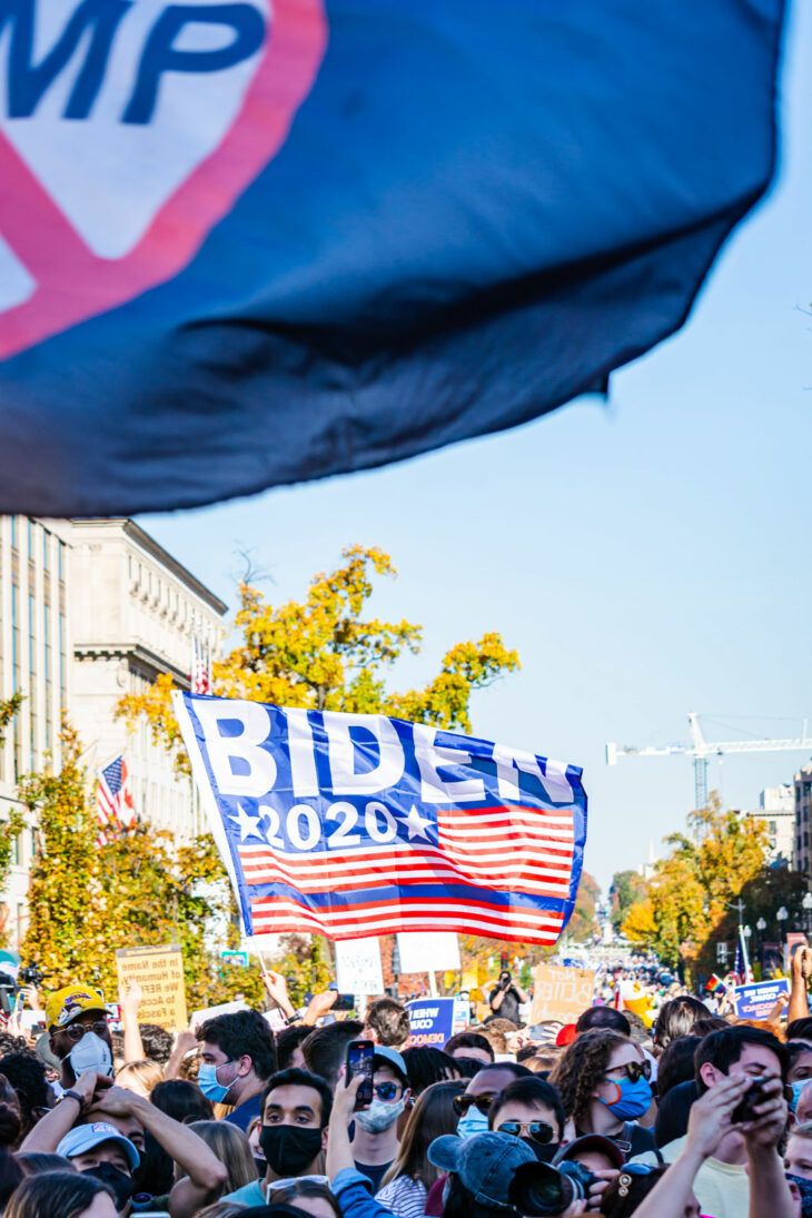 A group of Americans on the street waving a large Biden 2020 flag
